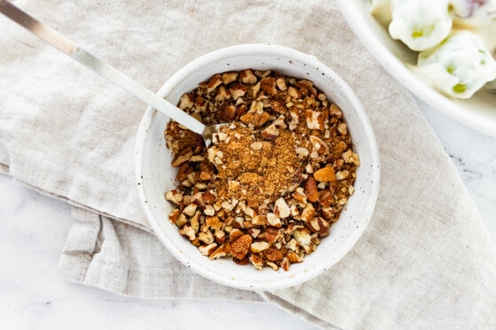 A small bowl with crushed pecans and coconut sugar.