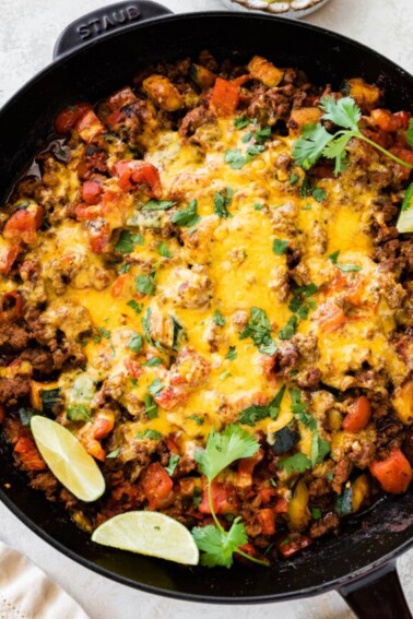 Ground beef and squash in a large skillet topped with melted cheddar cheese.