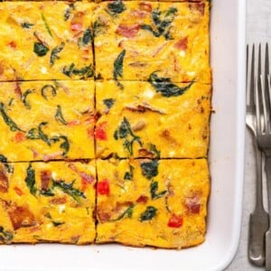 An egg casserole in a square baking dish. This casserole has been cut into square-sized pieces.