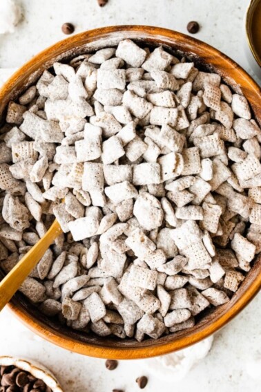 Puppy chow in a large wood bowl with a spoon.