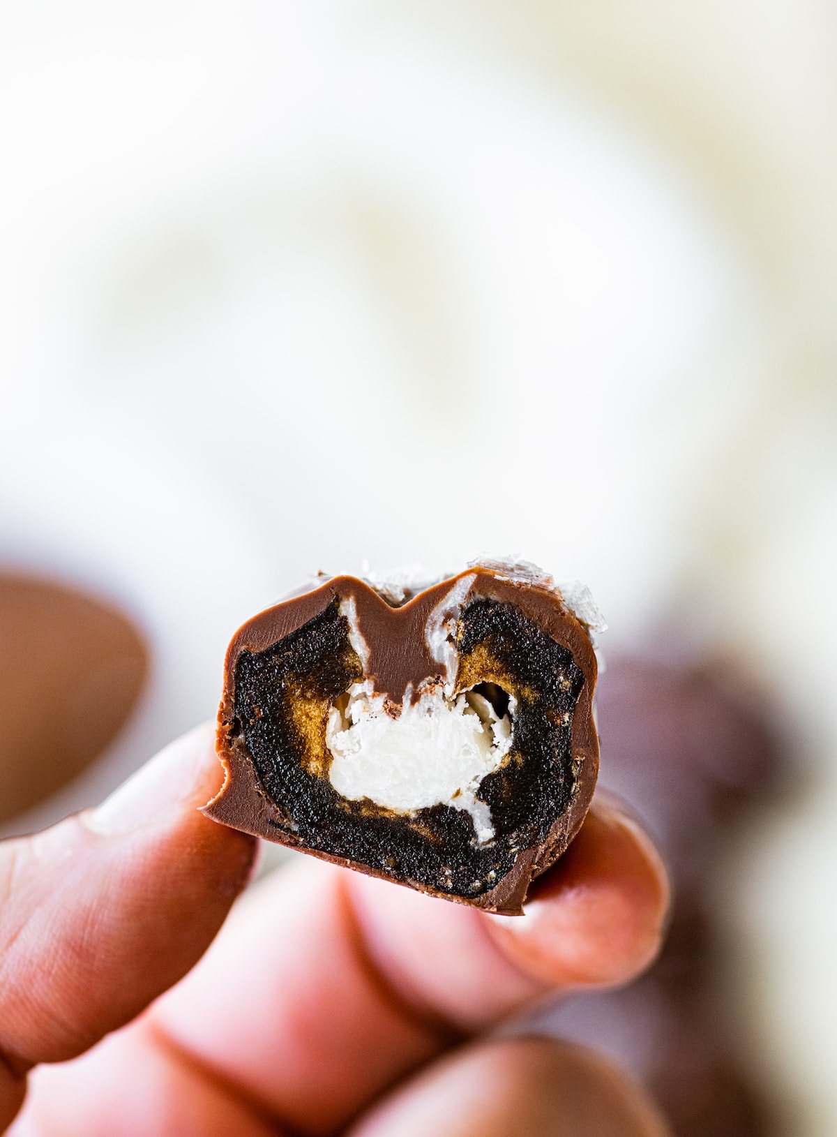 A woman's hand holding an open date mounds bar with a coconut filling.