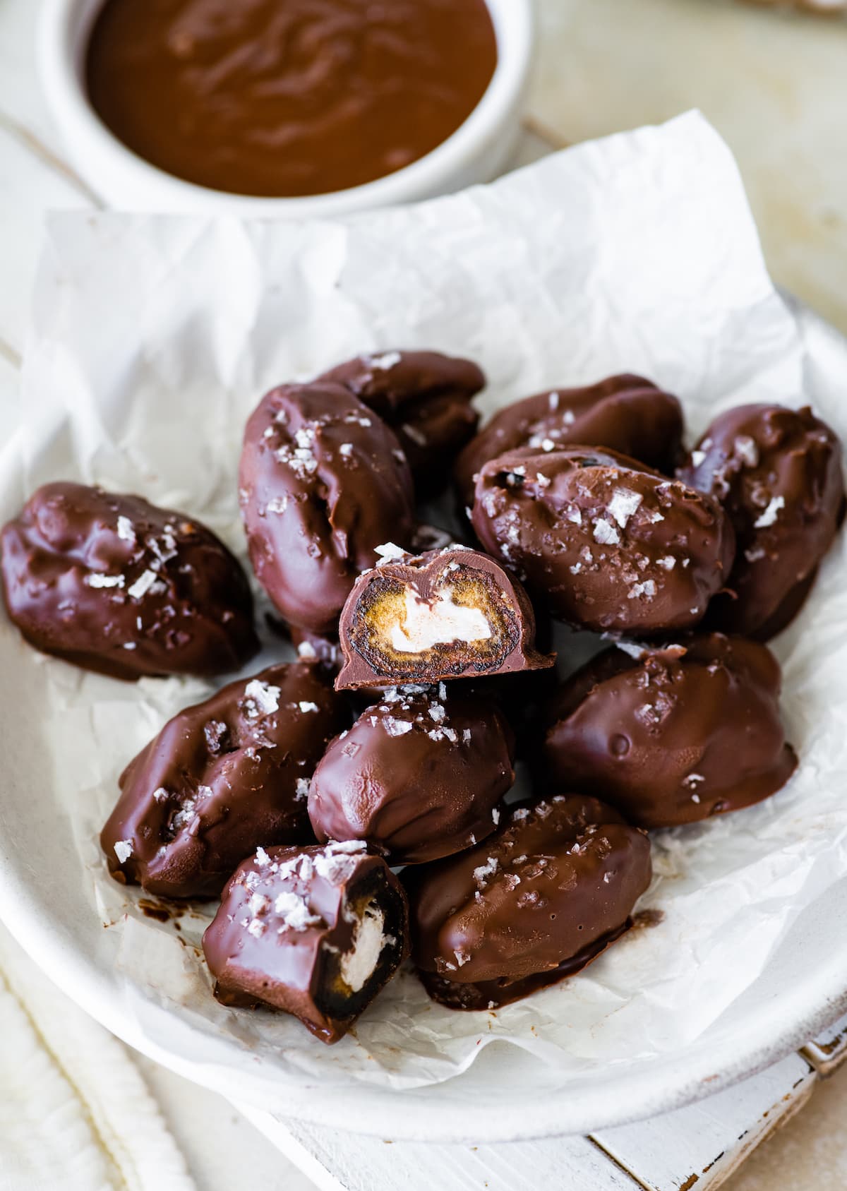 Multiple date mounds bars on a plate with one bar open up and showing the coconut filling on the inside.