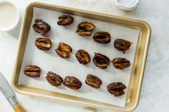 Split open Medjool dates on a baking tray.