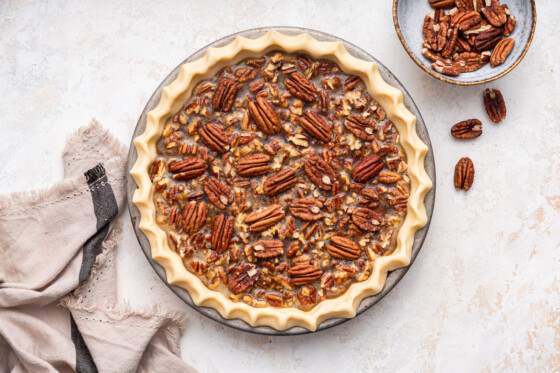 An unbaked pecan pie topped with pecan halves.