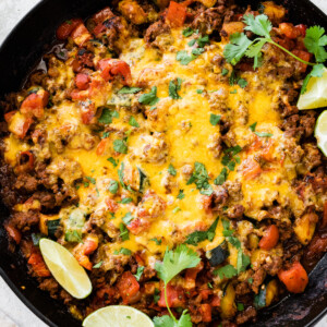 Ground beef and squash in a large skillet topped with melted cheddar cheese.