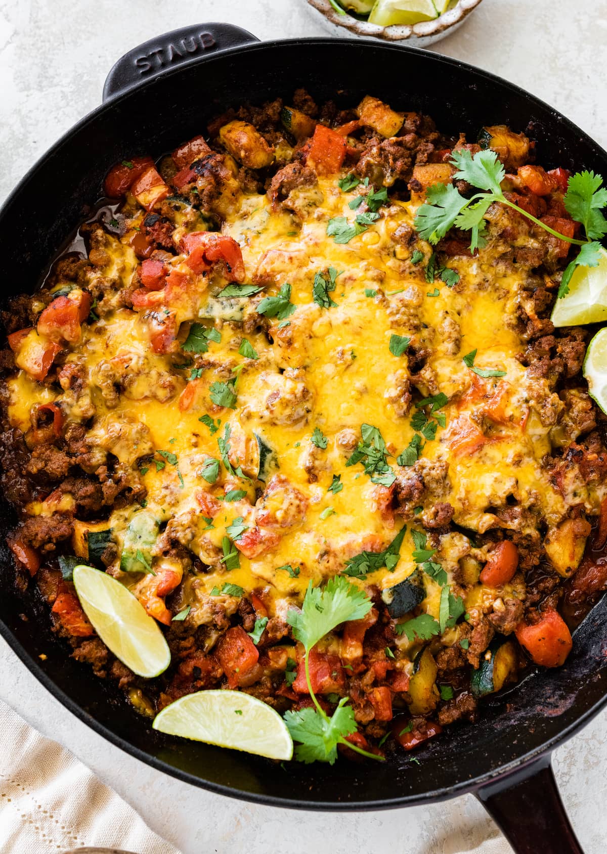 Ground beef and squash in a large skillet topped with melted cheddar cheese.