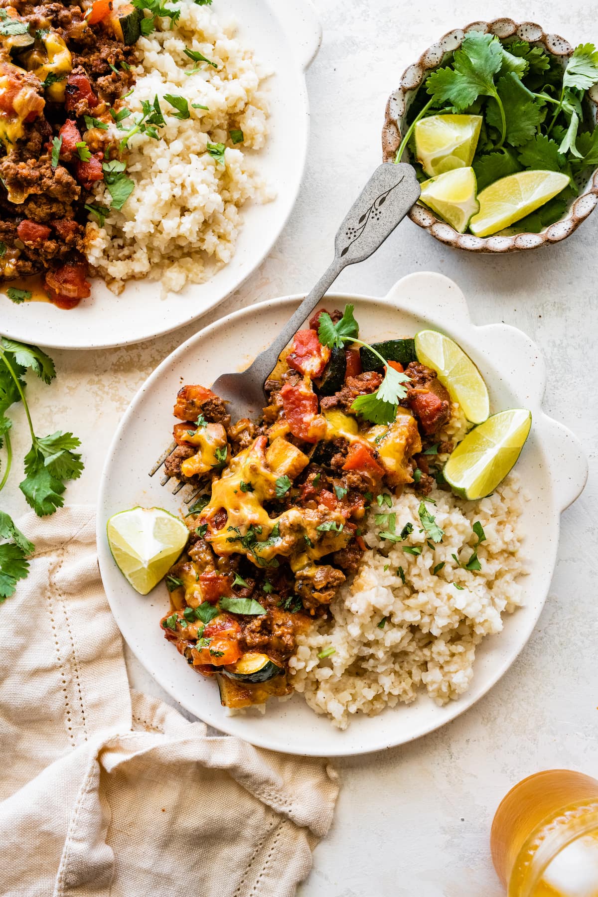 A serving of ground beef and squash skillet recipe on a plate with a side of brown rice and lime slices.