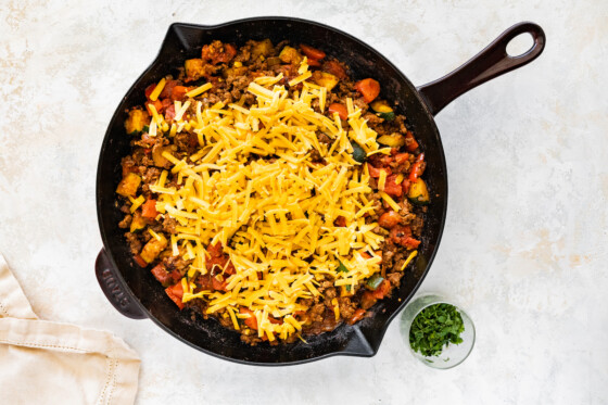 Shredded cheddar cheese added to the top of the ground beef and squash skillet.