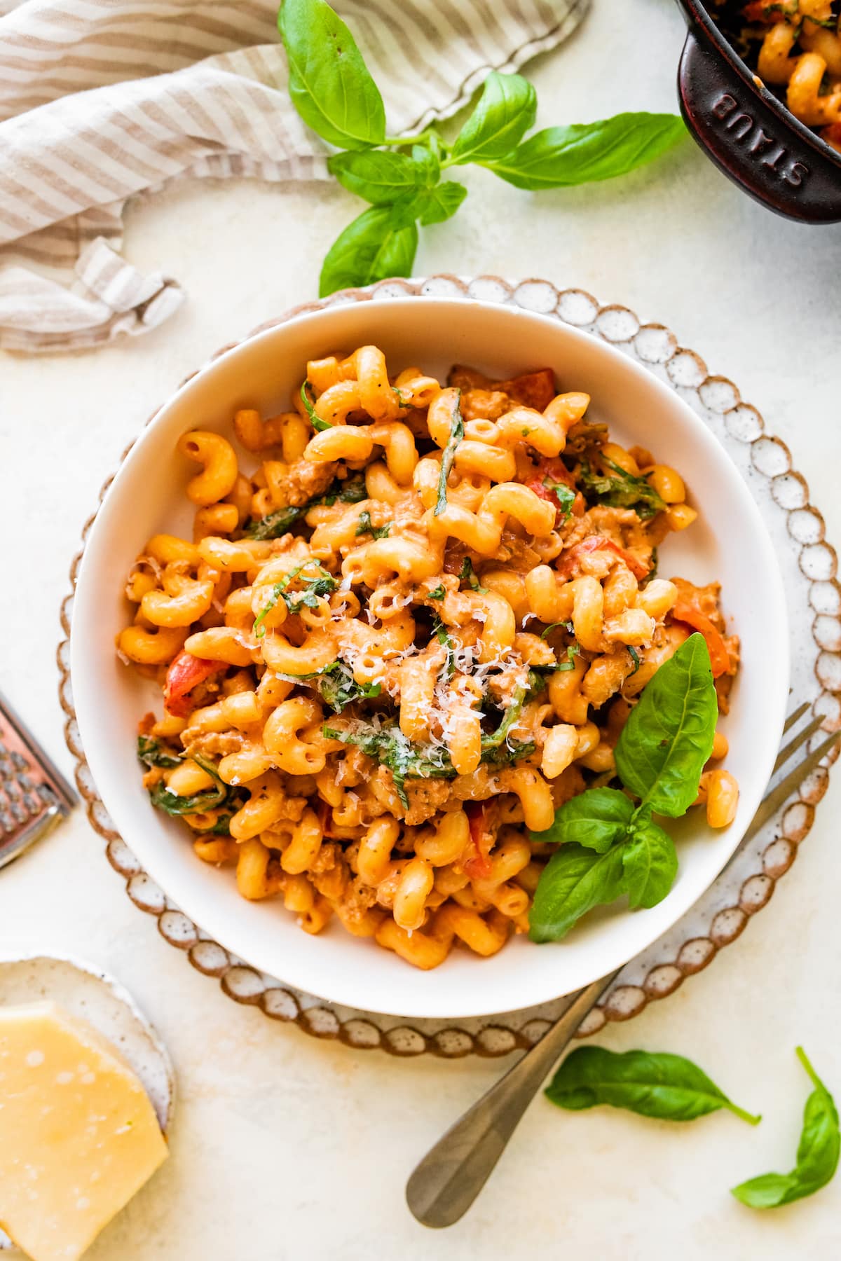 Ground turkey pasta in a bowl garnished with parmesan cheese and fresh basil.