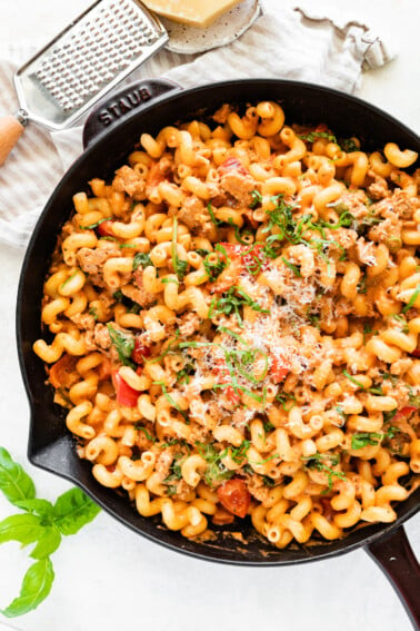 A large cast iron skillet with ground turkey pasta garnished with parmesan cheese.