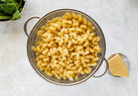 Cooked pasta noodles in a metal colander.