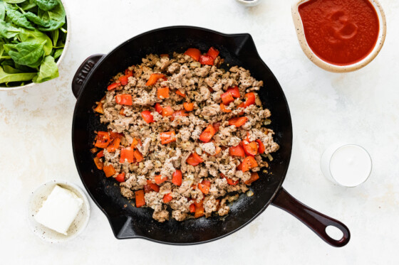 Diced red bell pepper, onion, garlic, and cooked ground turkey in a cast iron skillet.