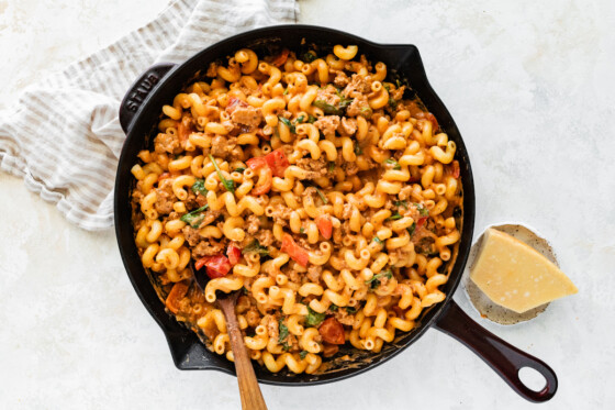 A large cast iron skillet with ground turkey pasta garnished with parmesan cheese.