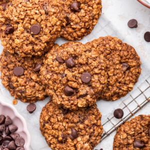 Chocolate chip lactation cookies on top of one another on a cooling wire rack.