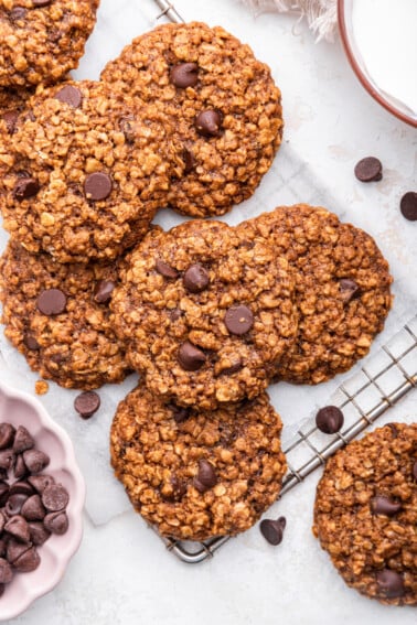 Chocolate chip lactation cookies on top of one another on a cooling wire rack.