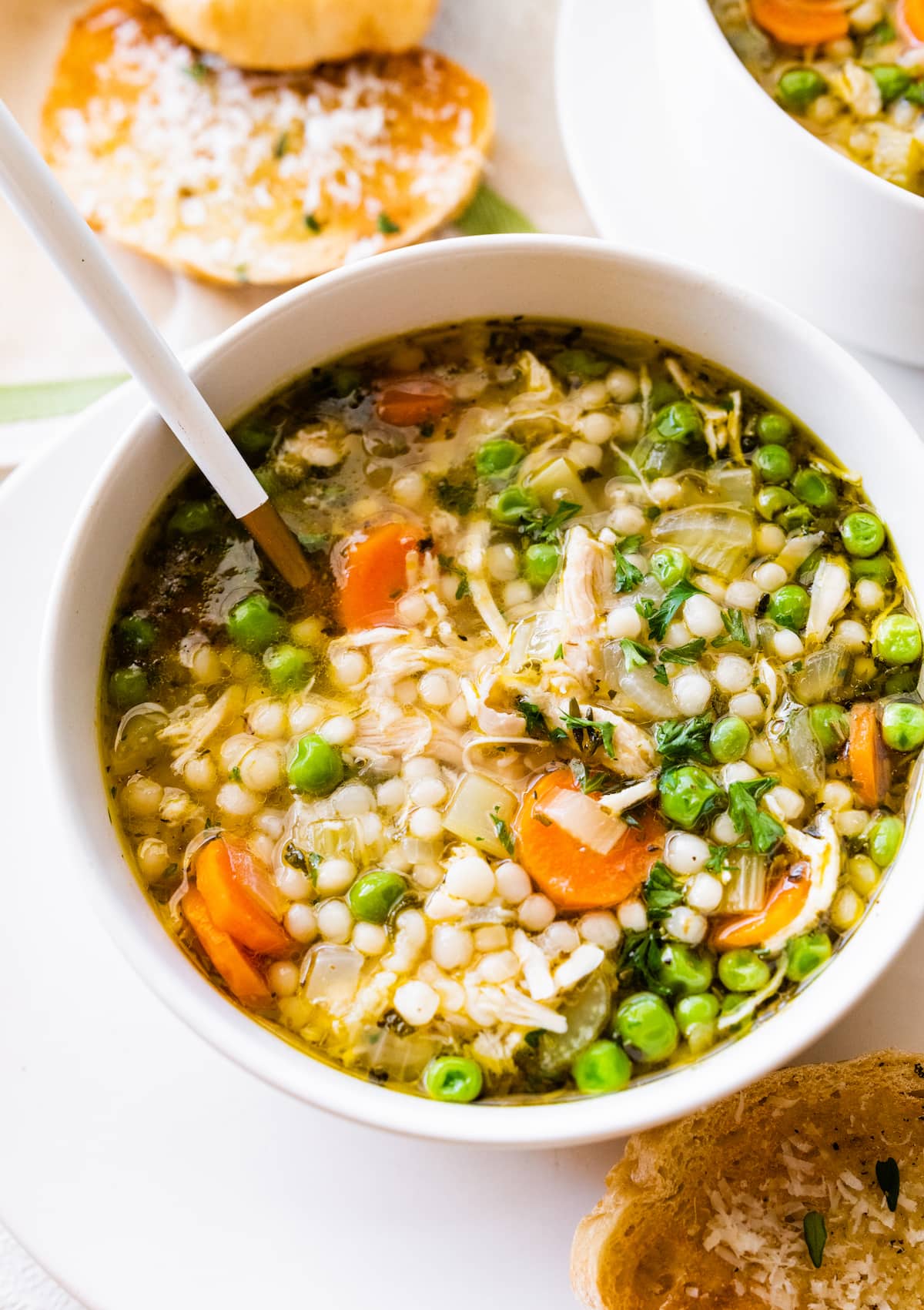 Leftover turkey soup in a bowl with multiple vegetables, including peas, carrots, and onions.