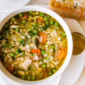 Leftover turkey soup in a bowl with multiple vegetables, including peas, carrots, and onions.