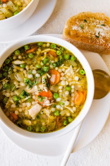 Leftover turkey soup in a bowl with multiple vegetables, including peas, carrots, and onions.