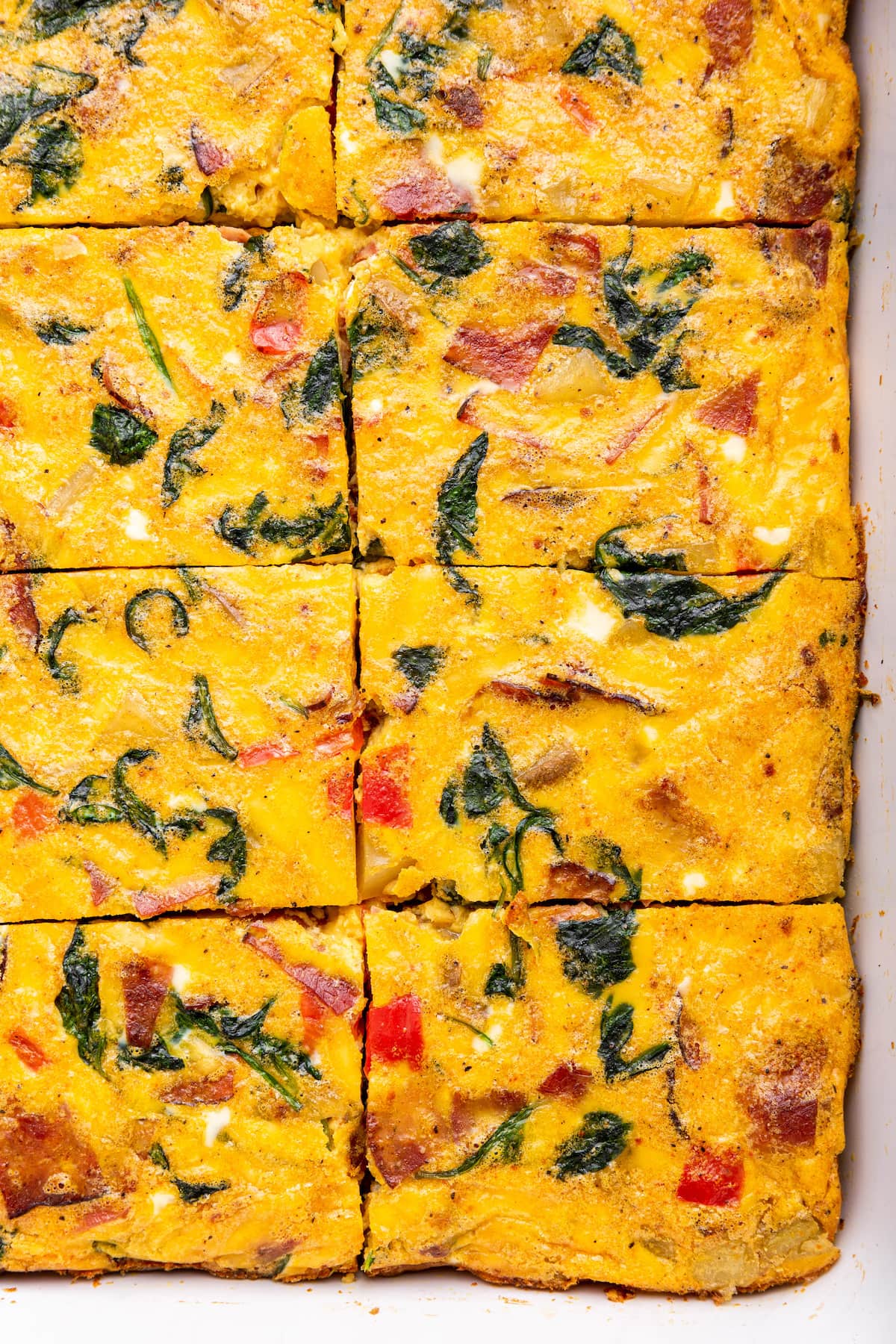 An egg casserole in a square baking dish. This casserole has been cut into square-sized pieces.