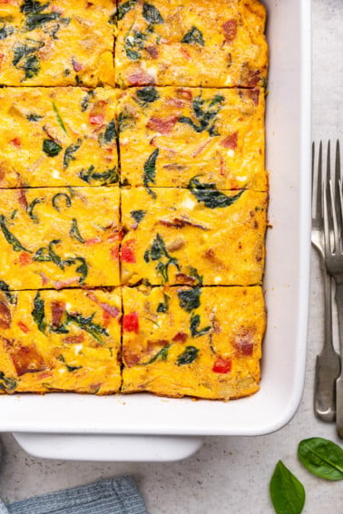 An egg casserole in a square baking dish. This casserole has been cut into square-sized pieces.