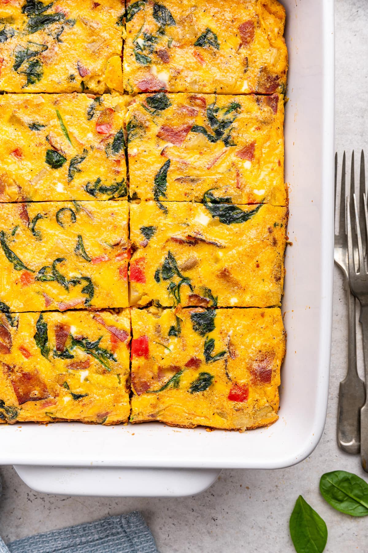 An egg casserole in a square baking dish. This casserole has been cut into square-sized pieces.