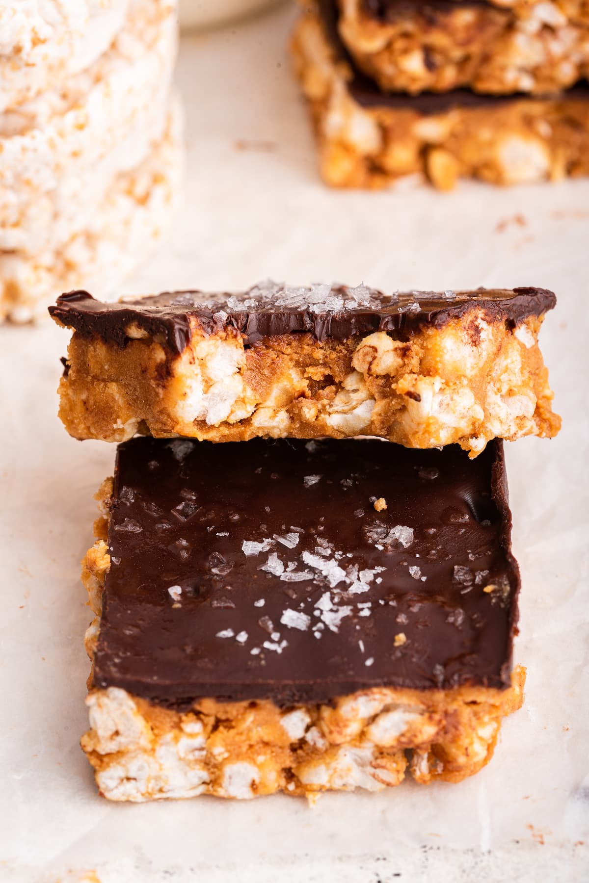 Two no bake peanut butter crunch bars stacked on one another with a bite taken from one.
