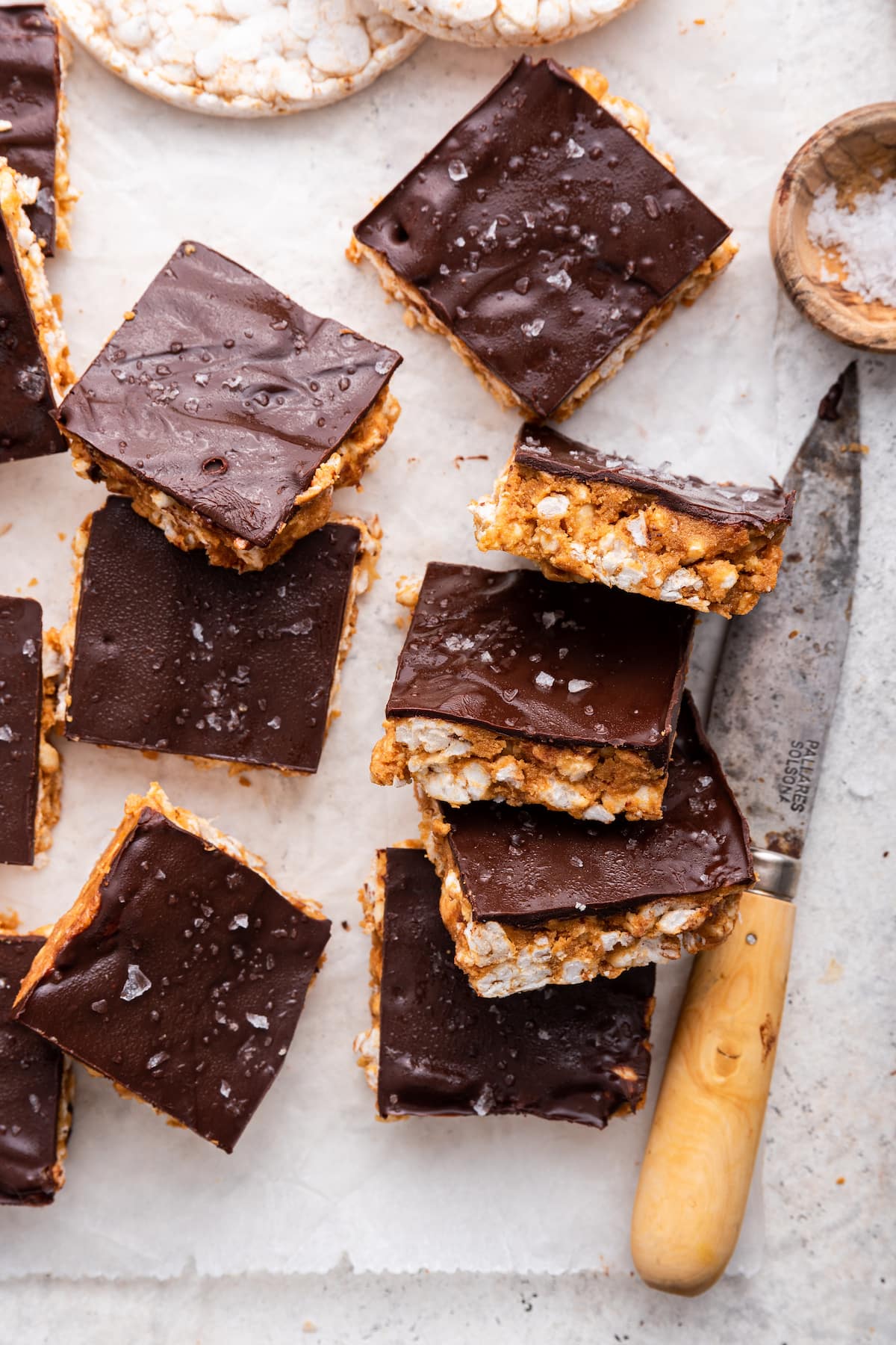Multiple no bake peanut butter crunch bars on parchment paper near a knife.
