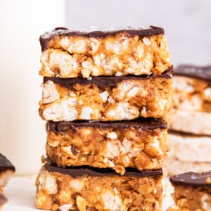 Four no bake peanut butter crunch bars stacked on one another.