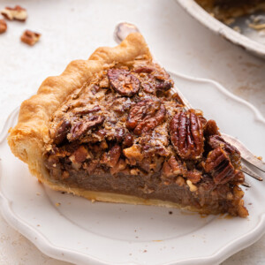 A slice of pecan pie on a plate served with a fork.