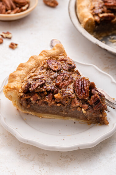 A slice of pecan pie on a plate served with a fork.