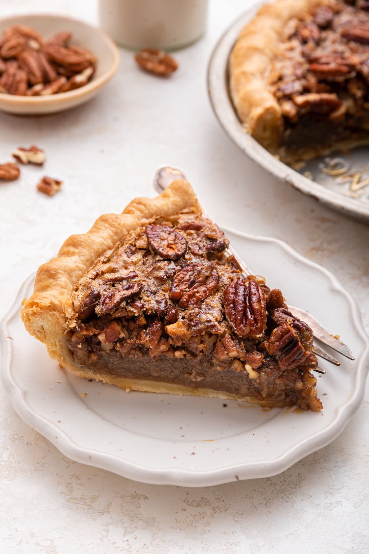 A slice of pecan pie on a plate served with a fork.