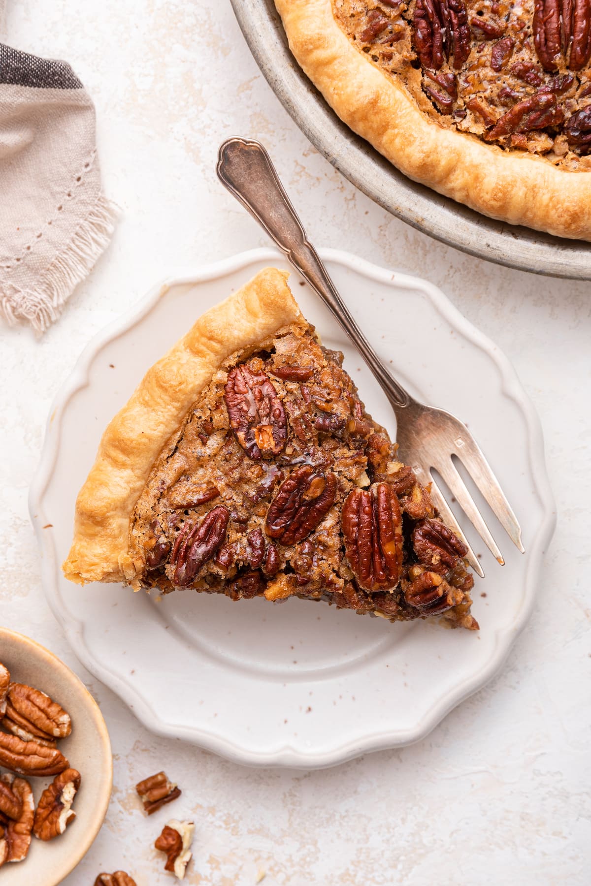 A slice of pecan pie on a plate served with a fork.