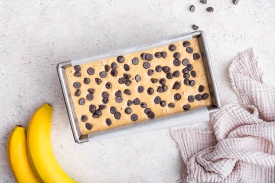 Protein banana bread batter in a bread pan topped with chocolate chips before being baked.