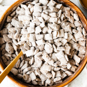 Puppy chow in a large wood bowl with a spoon.