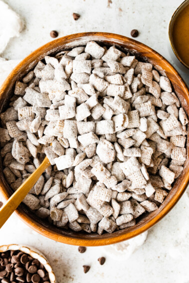 Puppy chow in a large wood bowl with a spoon.