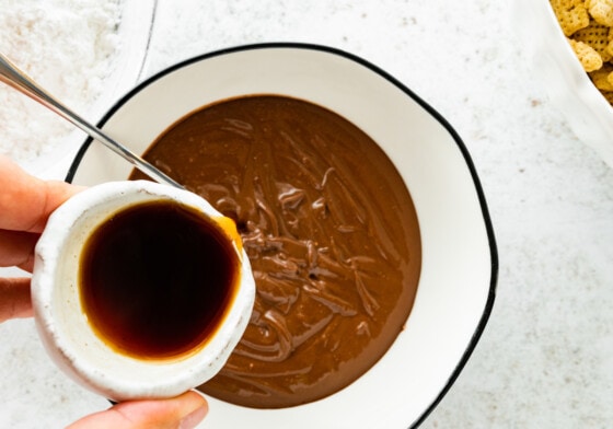 Maple syrup being poured into a bowl of melted chocolate.