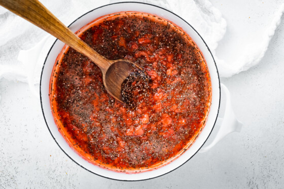 Strawberry chia jam in a large pot with a wooden spoon.