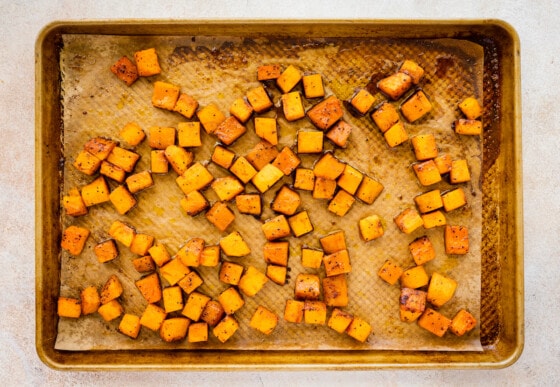 Cubed butternut squash on a baking tray after being roasted in the oven.