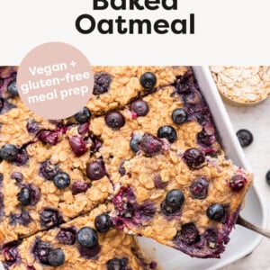 Blueberry Baked Oatmeal in a baking dish cut into slices. Serving spoon is holding a slice.