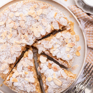 Almond cake on a large plate with three slices cut from the cake.