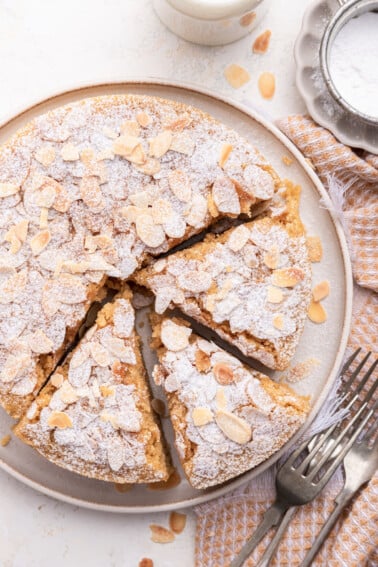 Almond cake on a large plate with three slices cut from the cake.