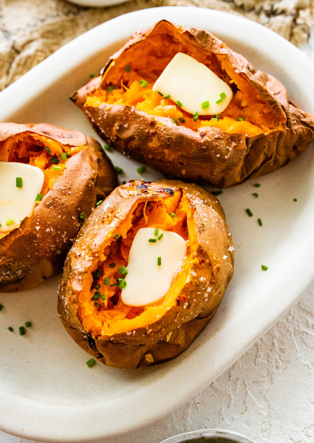 Three baked sweet potatoes split open with butter inside.