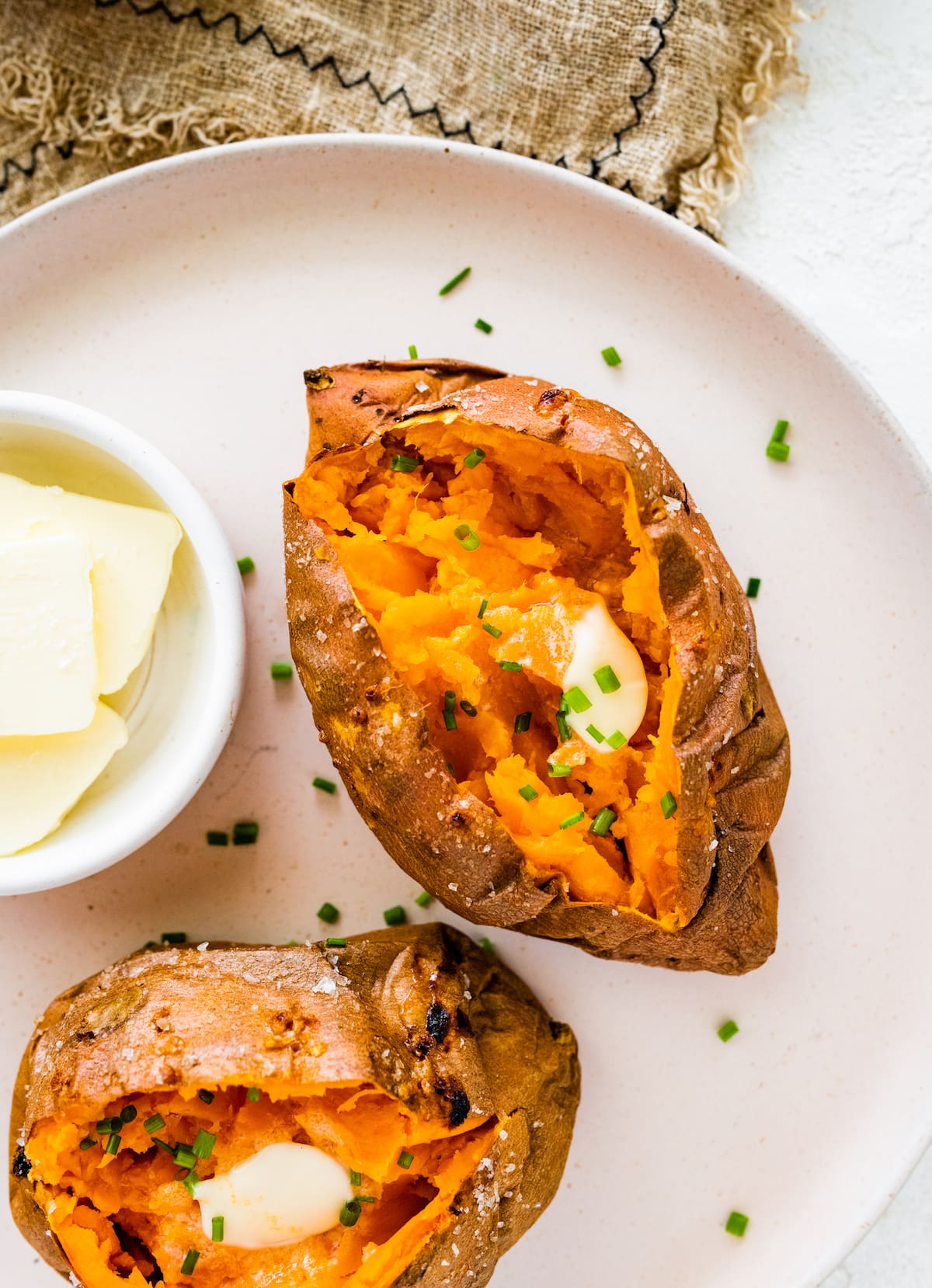 Two baked sweet potatoes split open with butter inside.