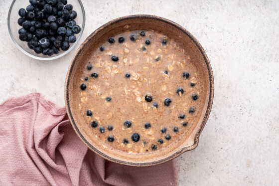 Fresh blueberries added to the blueberry baked oatmeal mixture in a large mixing bowl.