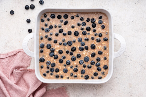 Blueberry baked oatmeal, before being baked, in a large square baking dish.