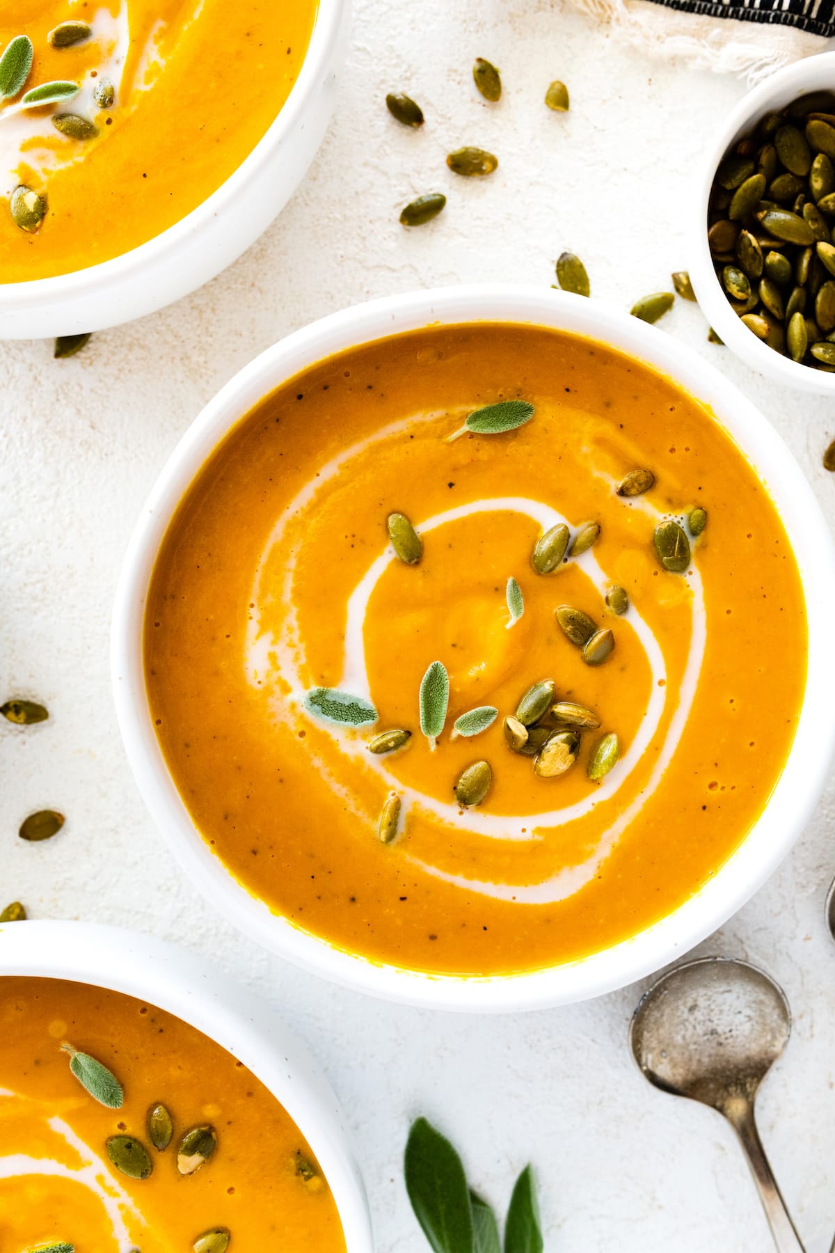 Butternut squash soup garnished with coconut milk, pumpkin seeds, and fresh sage.