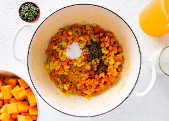 Seasoning is added to a large pot of veggies used for the butternut squash soup.