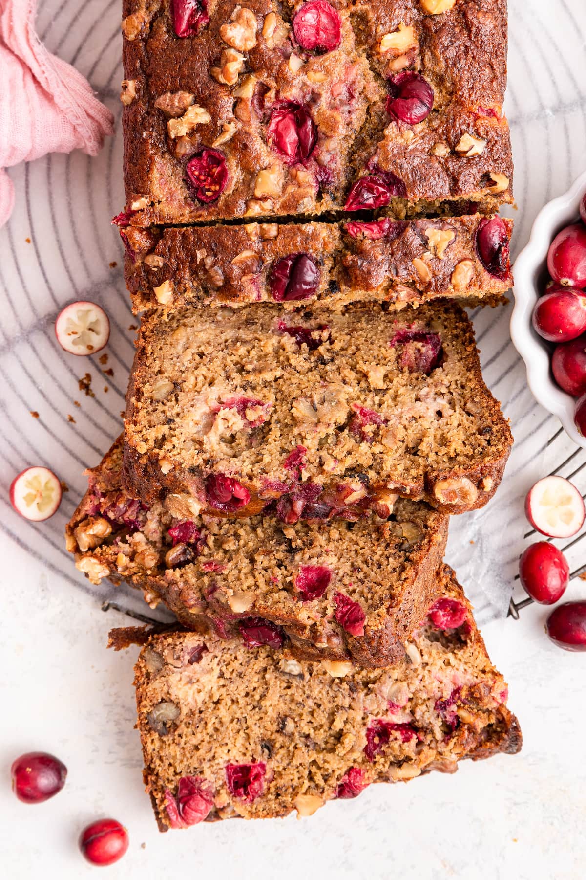 Three slices of cranberry banana bread leaning on one another near the loaf of bread.