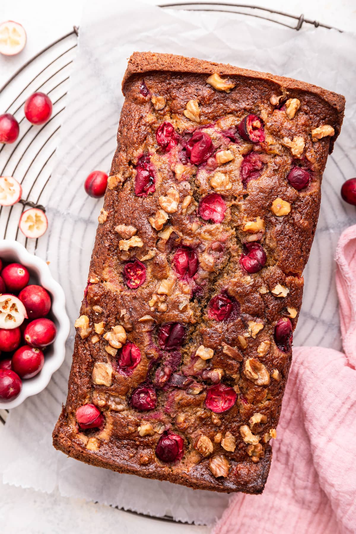 A loaf of cranberry banana bread on parchment paper.