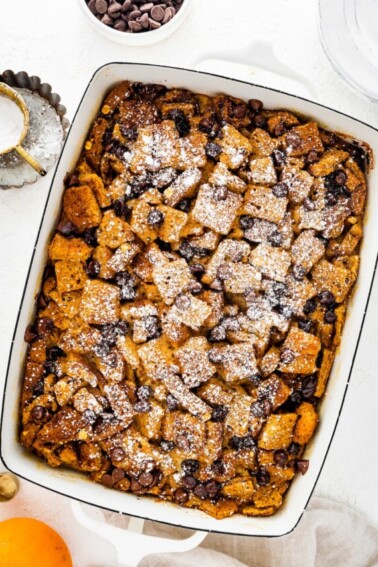 Pumpkin French Toast Casserole in a square baking dish topped with powdered sugar and chocolate chips.
